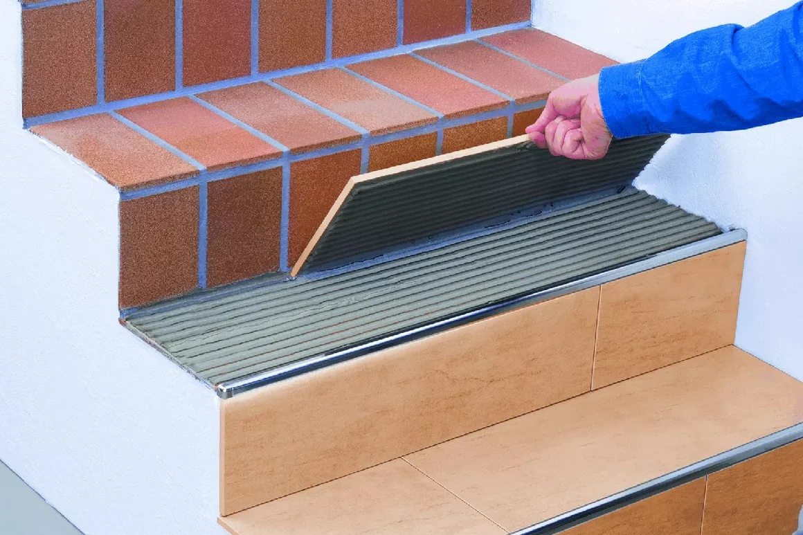 Person verlegt Fliesen auf Treppe